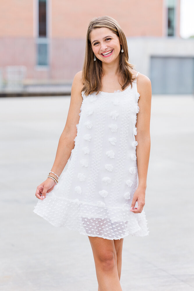 Smiling high school senior girl with pretty white summer dress.