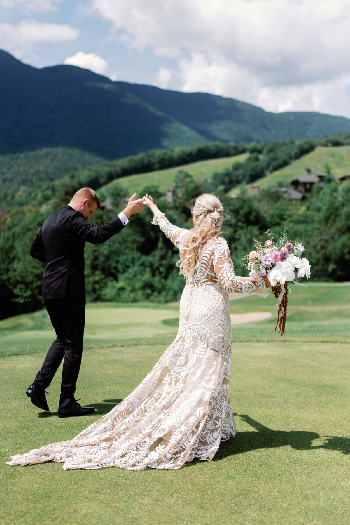 spruce peak lodge wedding couple on golf course walking toward green mountains by jaclyn watson events