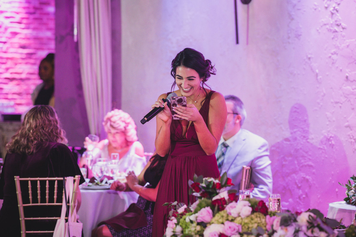 bridesmaid laughing while reading speech during wedding reception at The Loft by Bridgeview