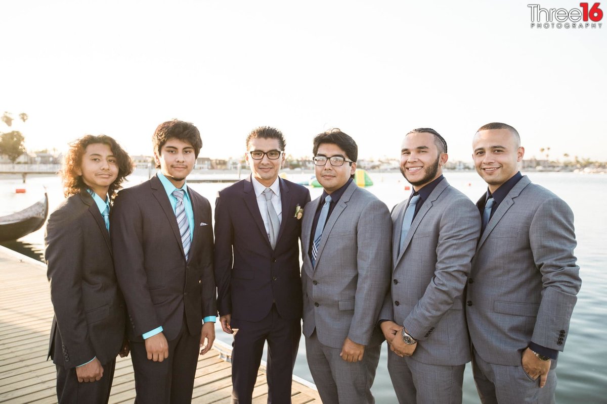Groom and his groomsmen pose together with the ocean behind them