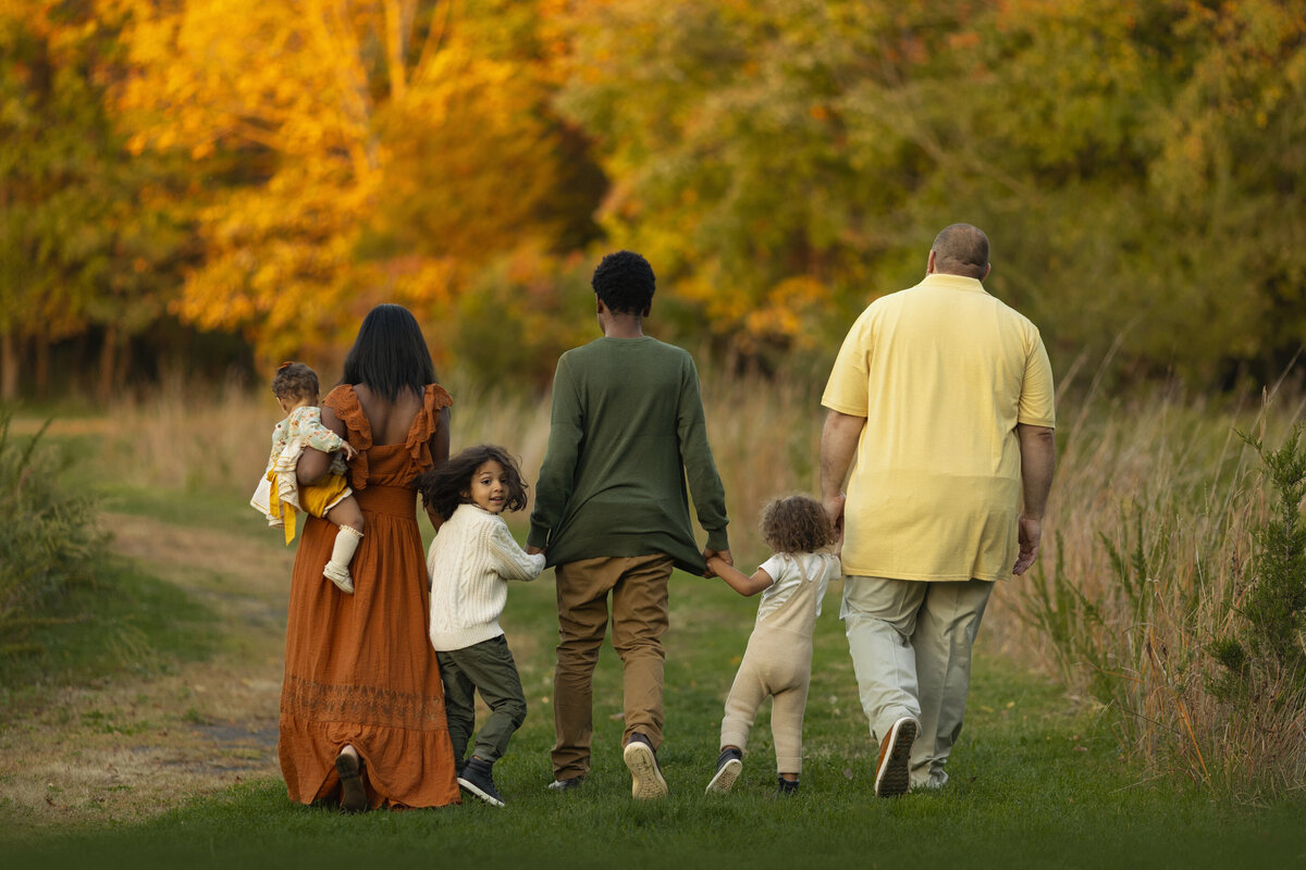 A New Jersey Family Photographer image of a family of six walking through a park trail at sunset