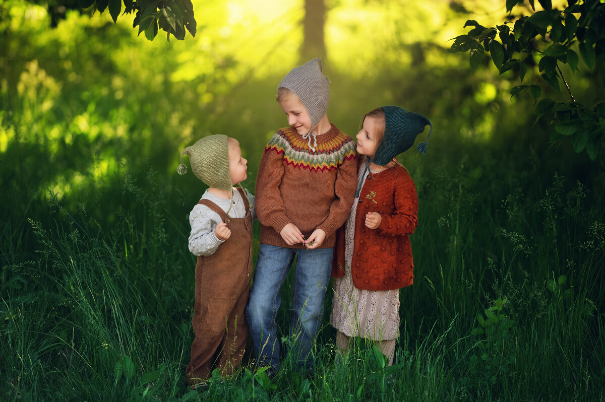 Three siblings pose for a whimsical portrait in stylized clothing straight from a storybook.