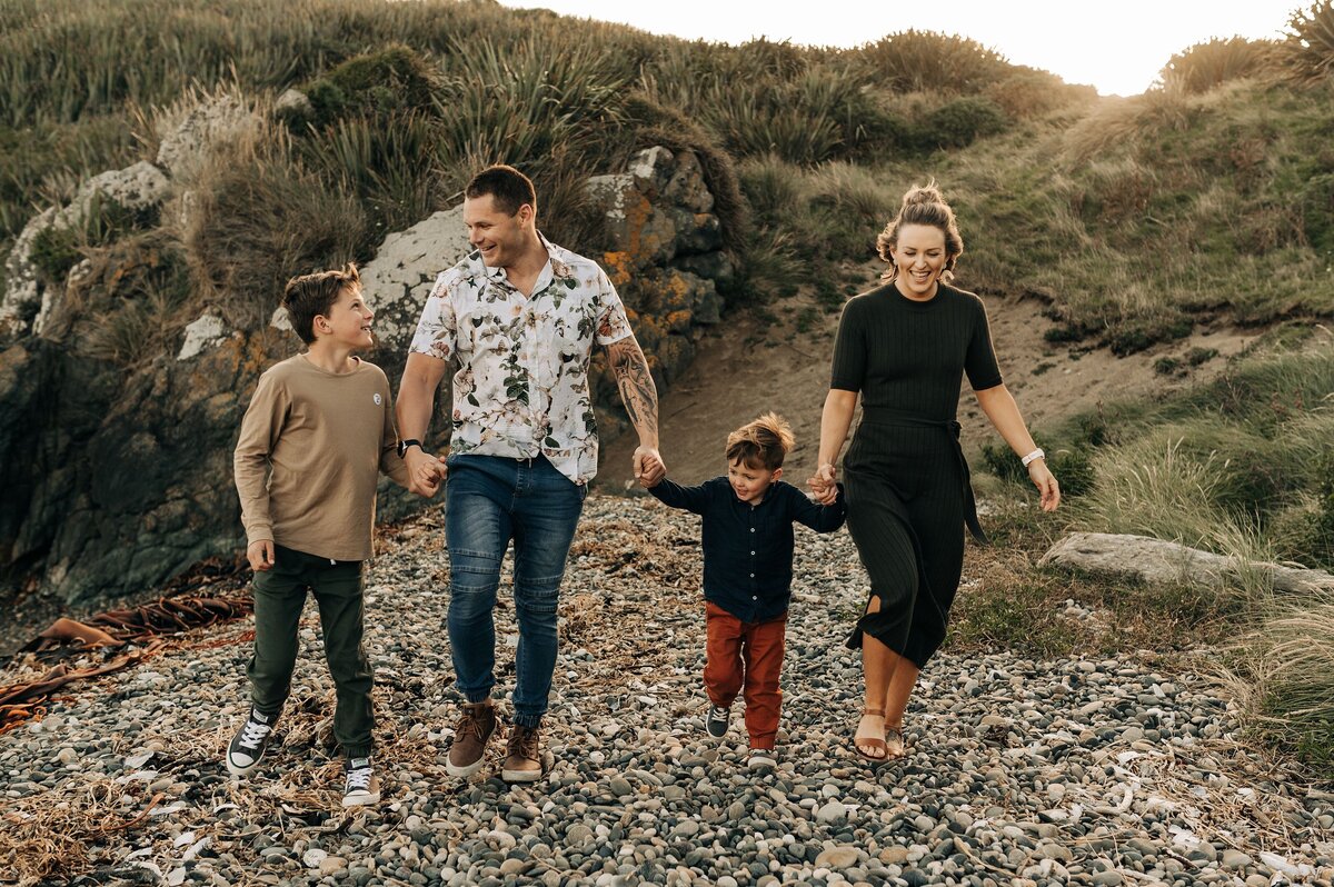 family four beach riverton new zealand sunset engaged two boys hold hands walking