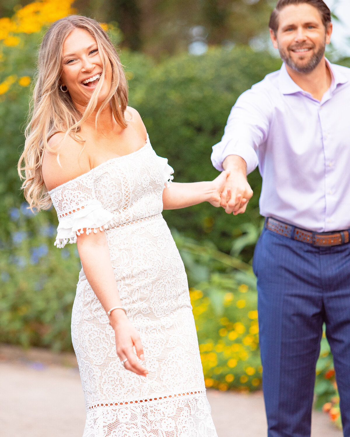 Woman laughs as groom holds her hand during their engagement session at Harkness State Park.