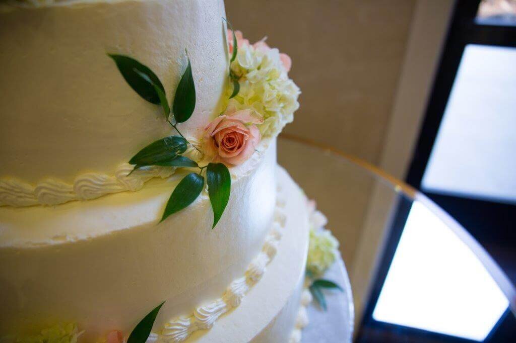 Close up of wedding cake that is white with pink flowers on it.