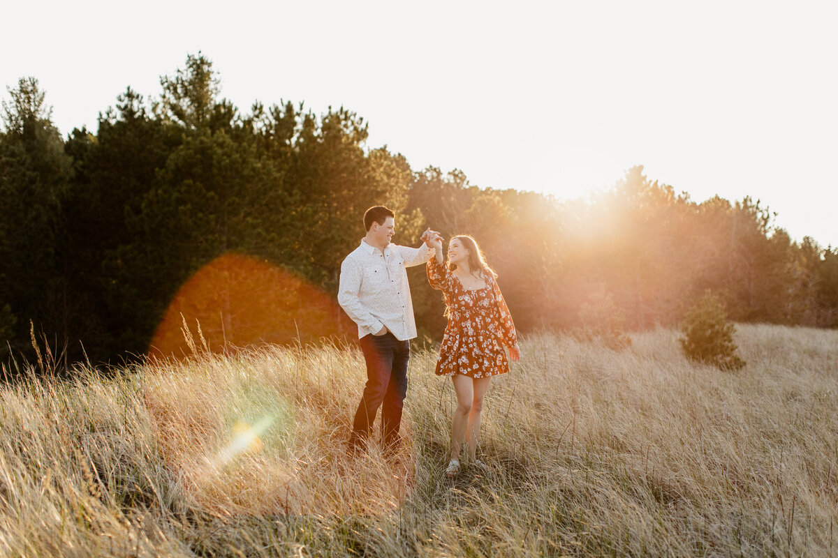 A couple dances in a field during their Wisconsin engagement session at Wisconsin Beach, surrounded by Lake Superior. Photo taken by Minnesota Wedding Photographer, Morgan Elizabeth Photography www.morganelizabethphoto.com @morganelizabethphotos