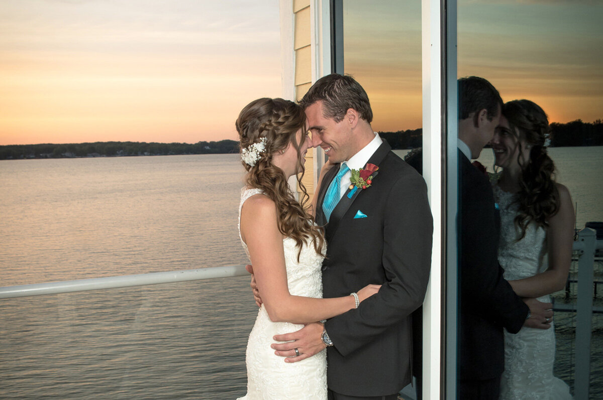 Bride and groom embrace and smile at their waterfront wedding