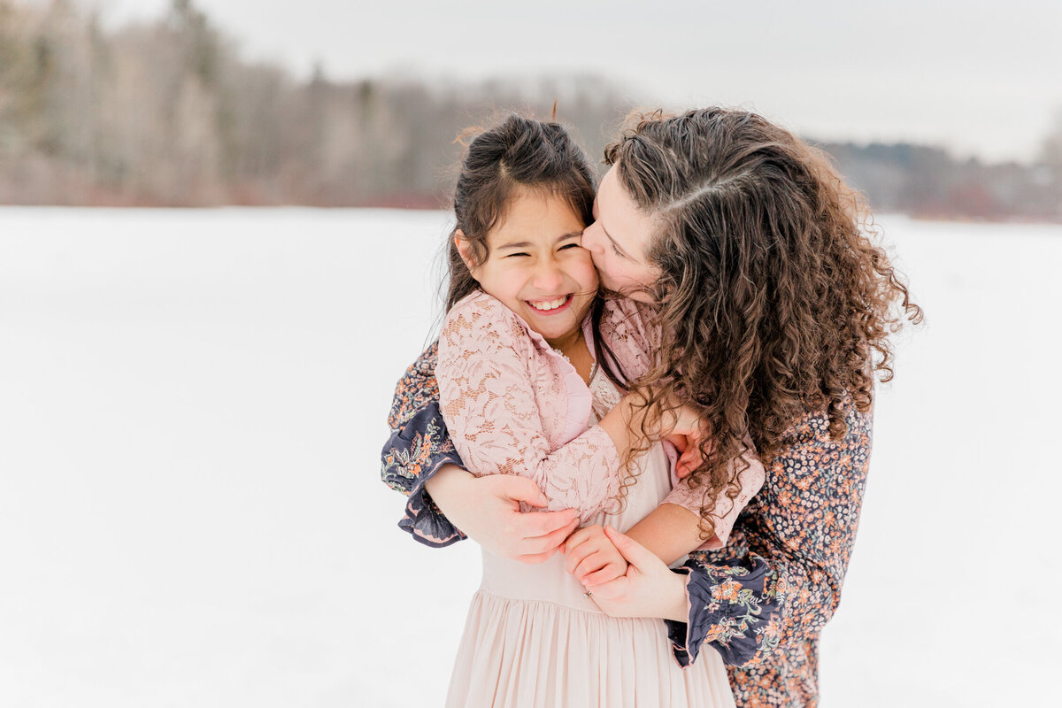 Family Photography Session in Massachusetts | Mother hugging laughing daughter in a snowy field