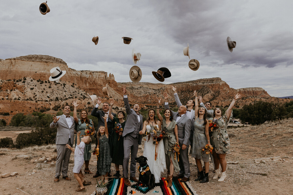 wedding party throwing their hats in front of red rocks