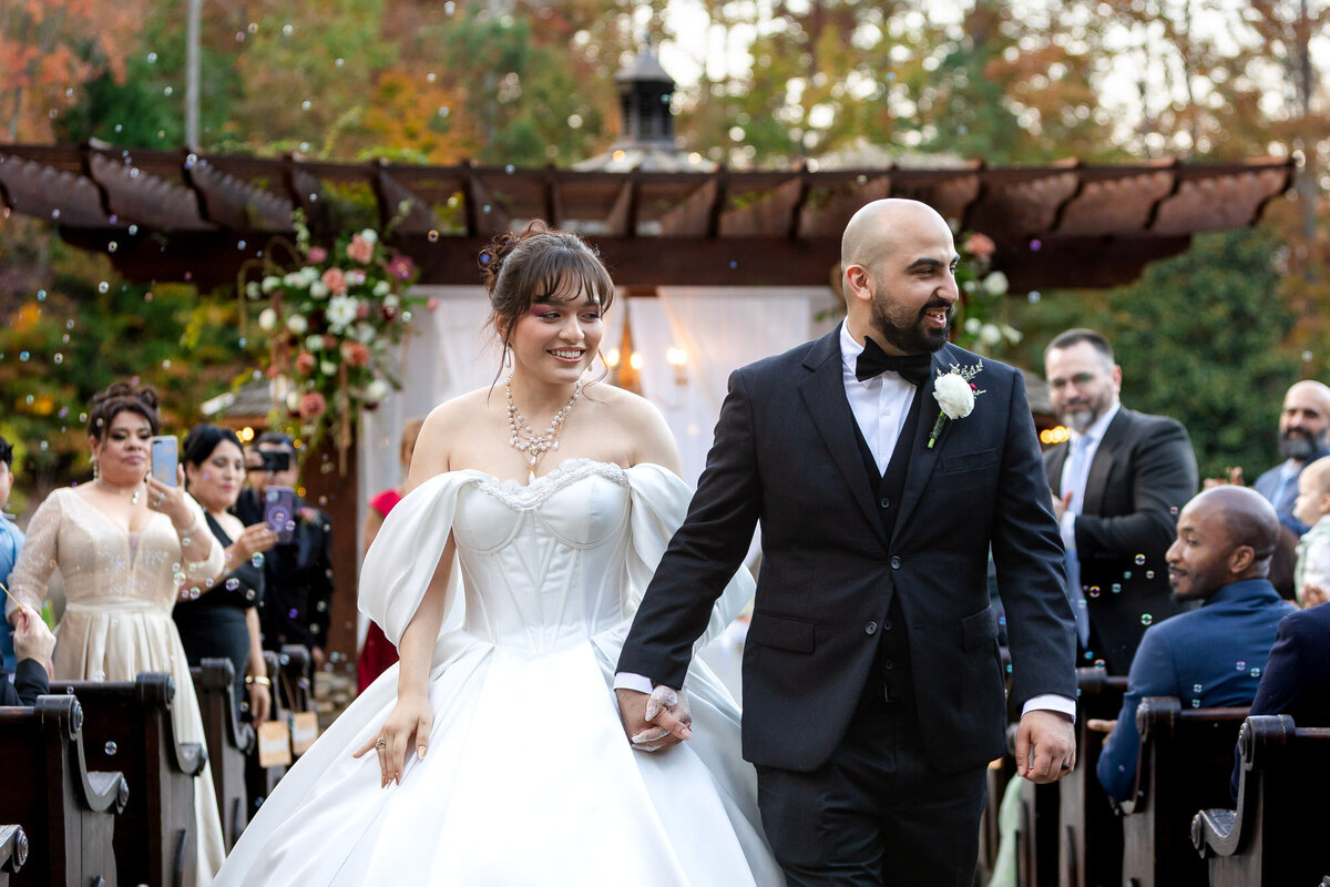 a recently married couple walking down the aisle after their wedding at Rocky's Lake Estate