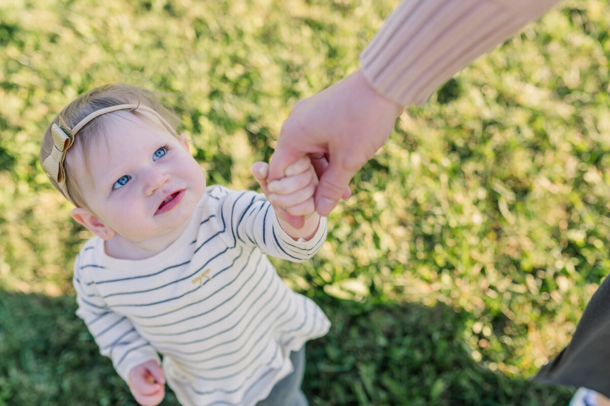 Baby-with-blue-eyes-holding-moms-hand-looking -up-to-her