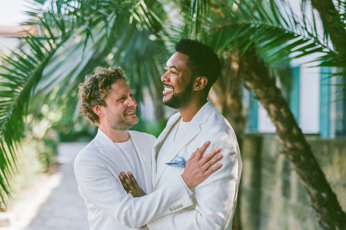 Two grooms smiling and holding each other.