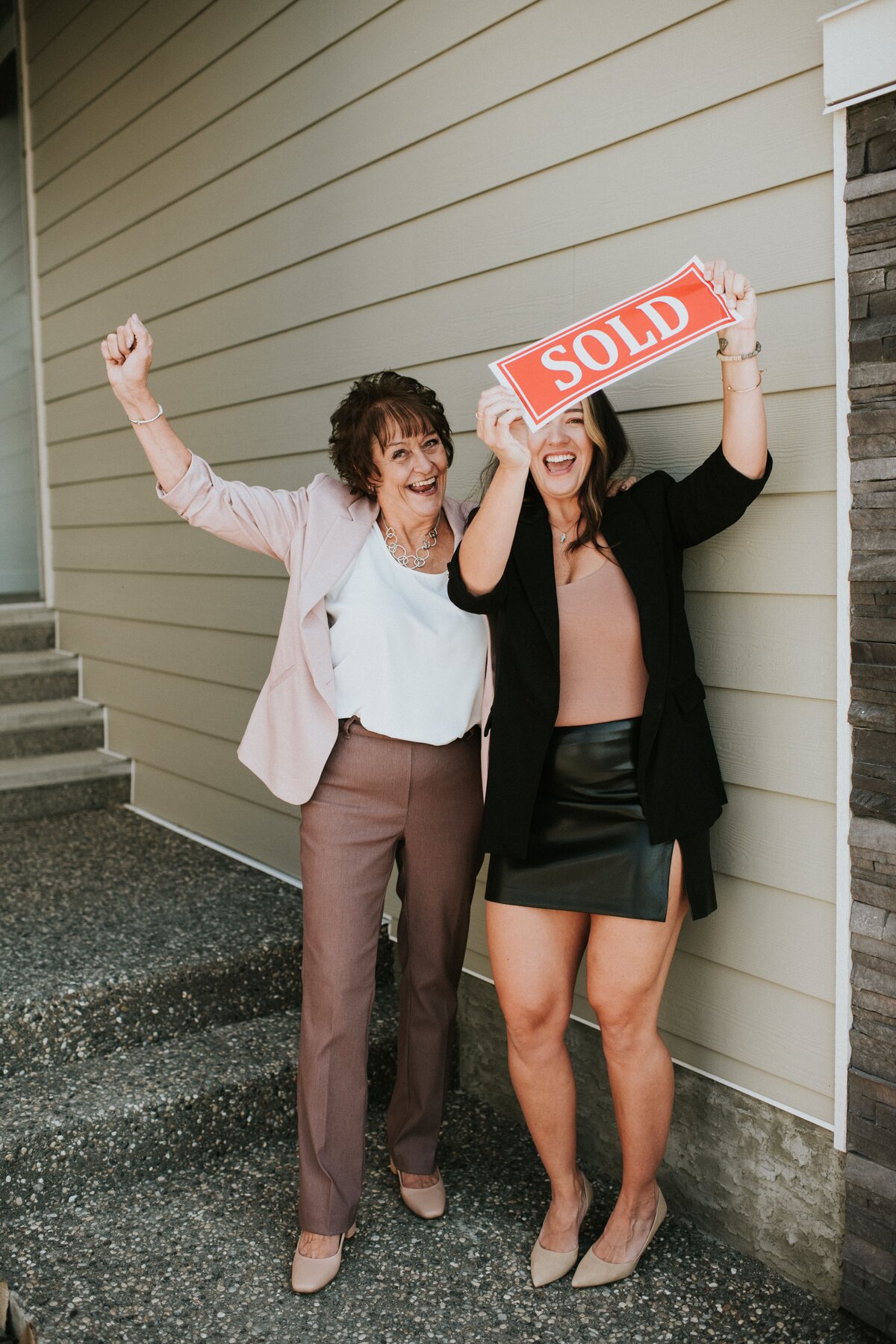 two women holding a sold sign