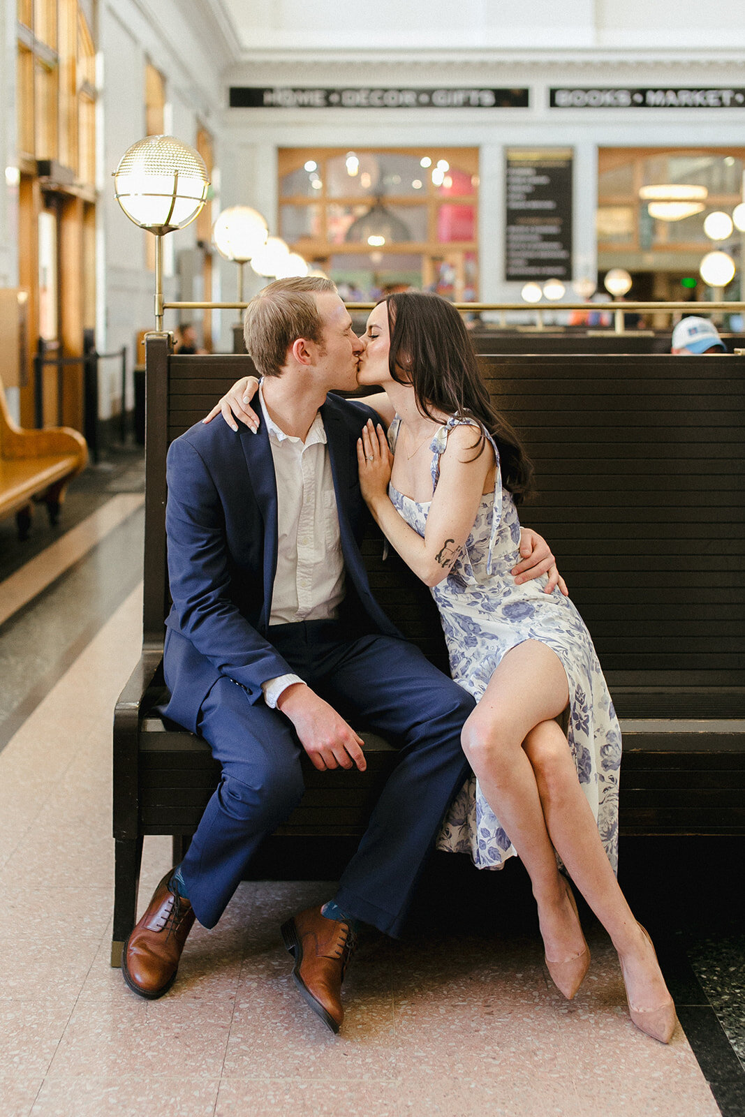 Couple kiss at Union Station in Denver, Colorado. Bride wears a floral Reformation dress and groom wears a blue suit.