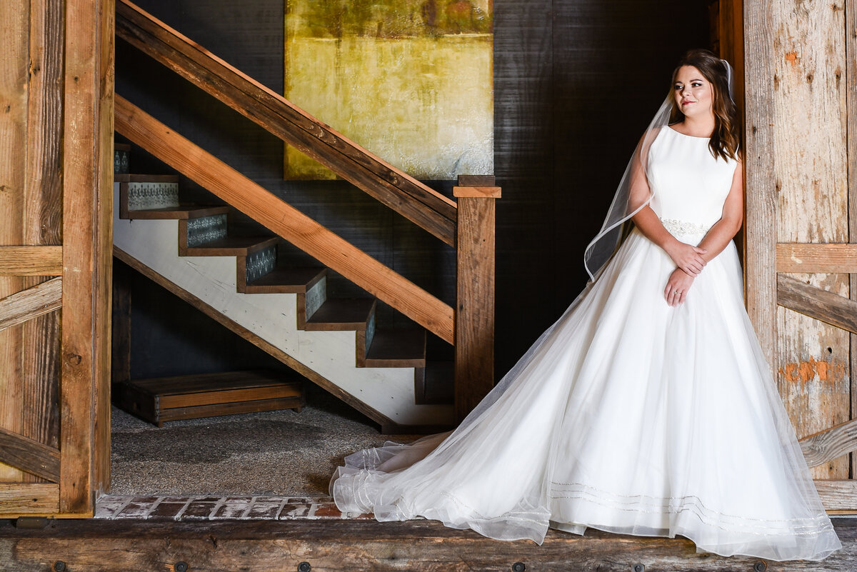 Beautiful bridal portrait photography: Bride leans in a dramatic doorway with chandelier behind at Greengates Farmhouse in MS