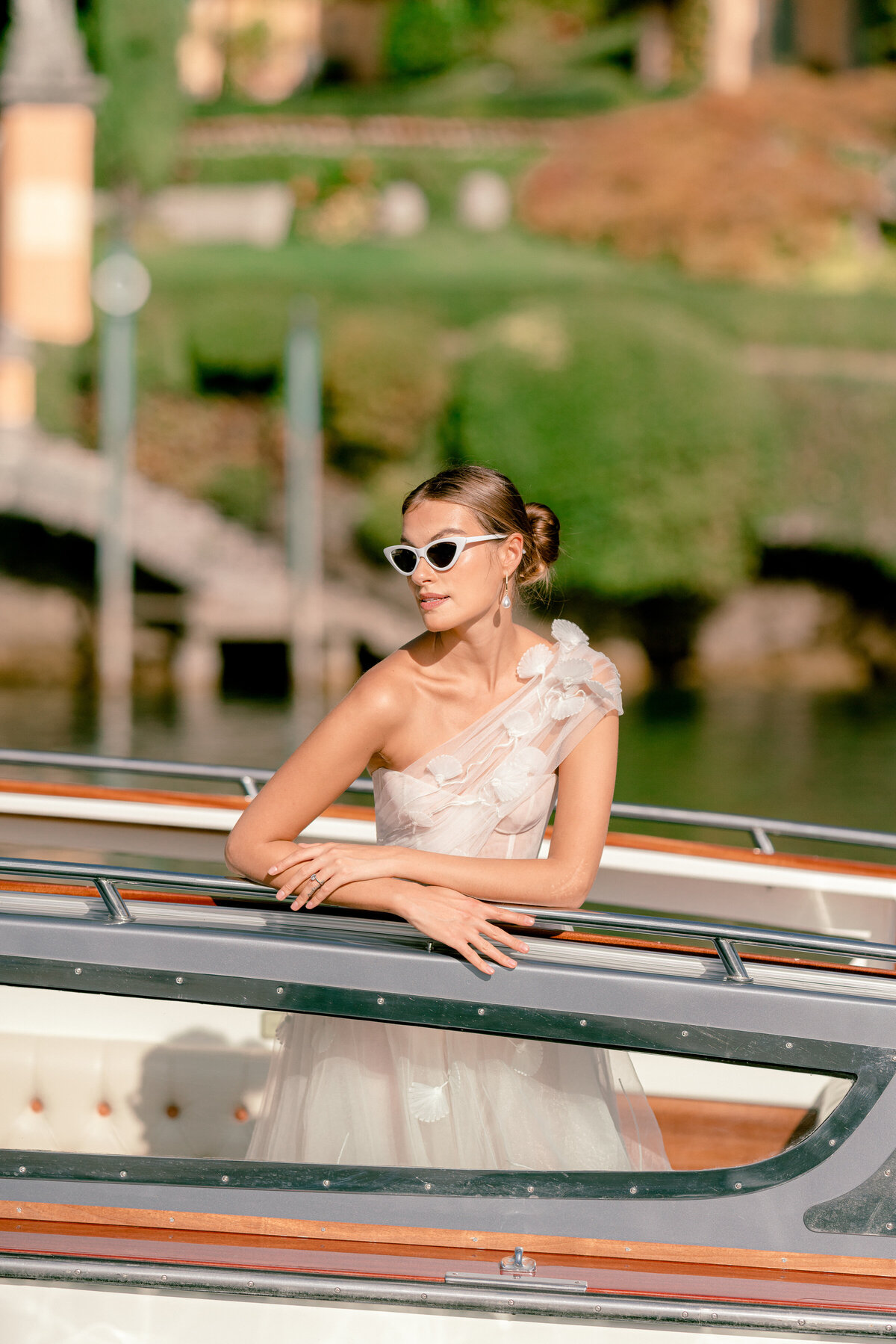 Bride wearing white sunglasses on a private boat on lake como, italy