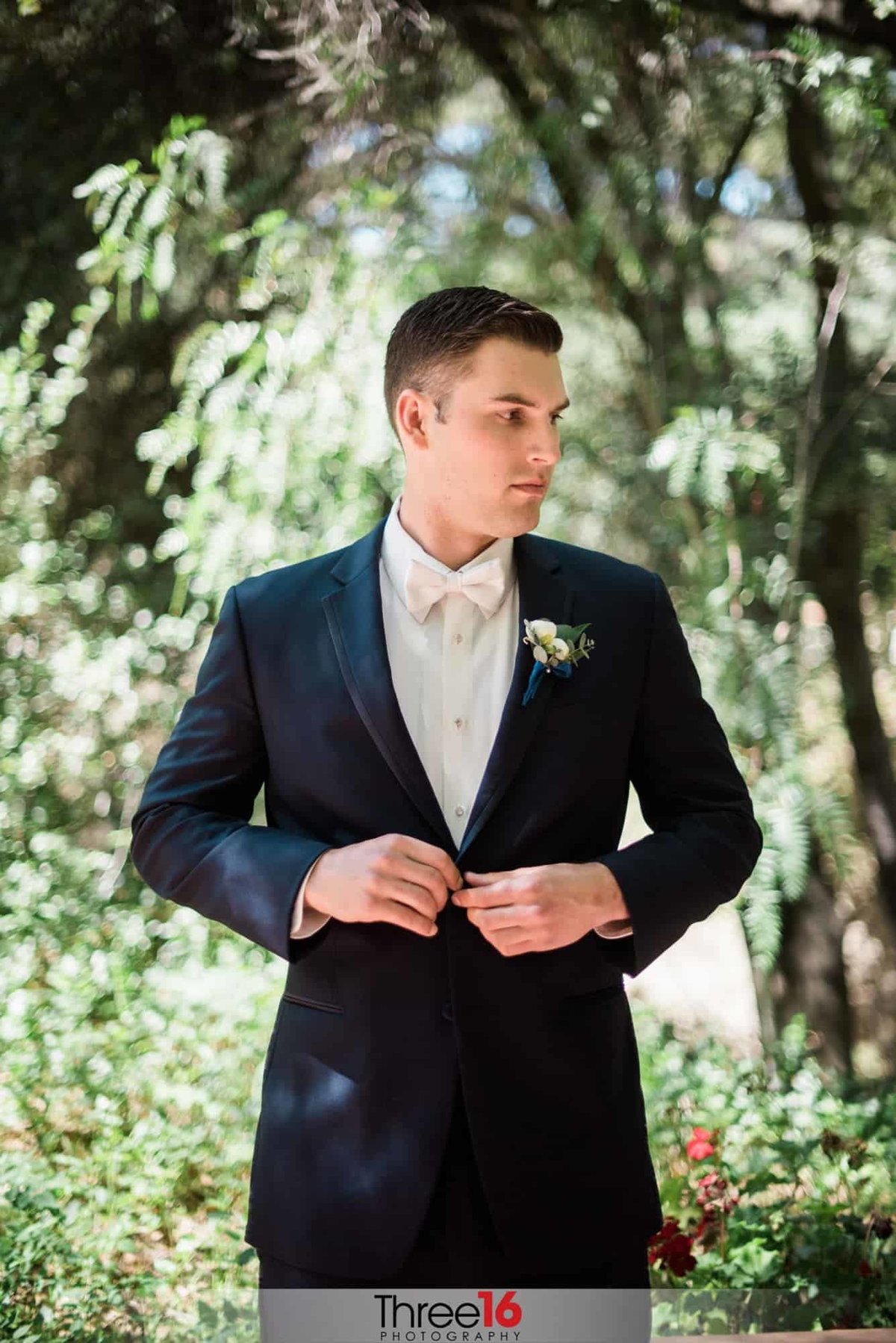 Groom buttons up his suit jacket just prior to the start of his wedding ceremony