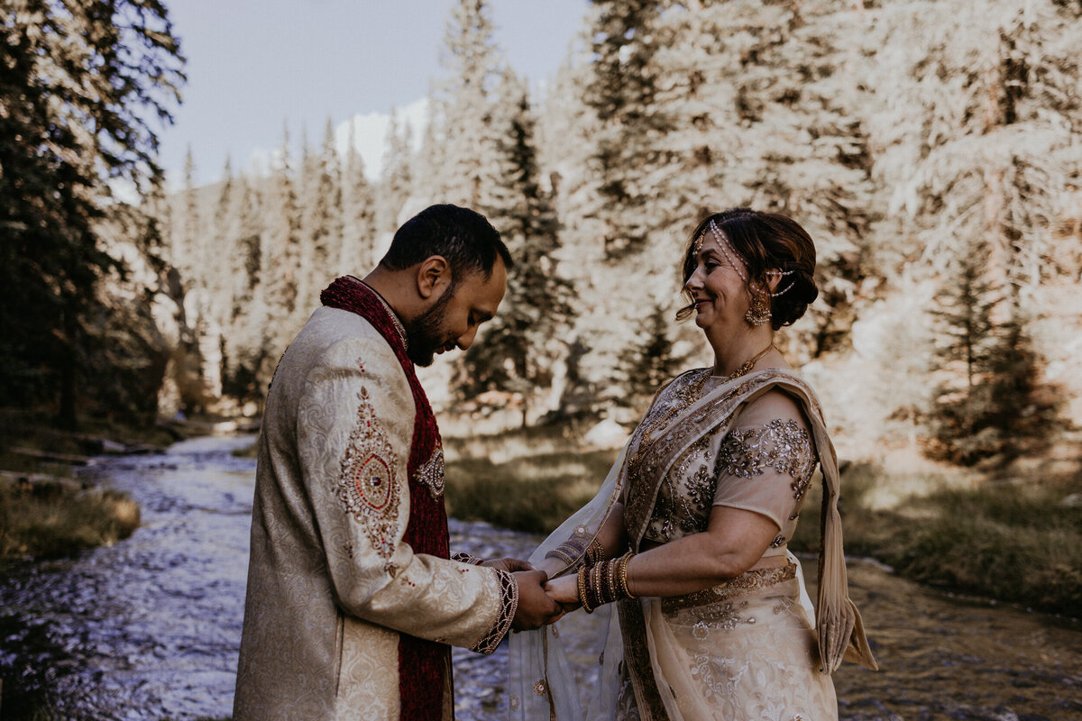 bride and groom exchanging vows in front of a creek