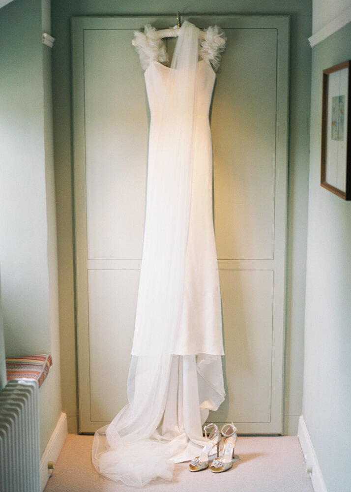 simple minimalist wedding dress with fluffy tulle straps together with bridal veil hanging over the dress and shoes