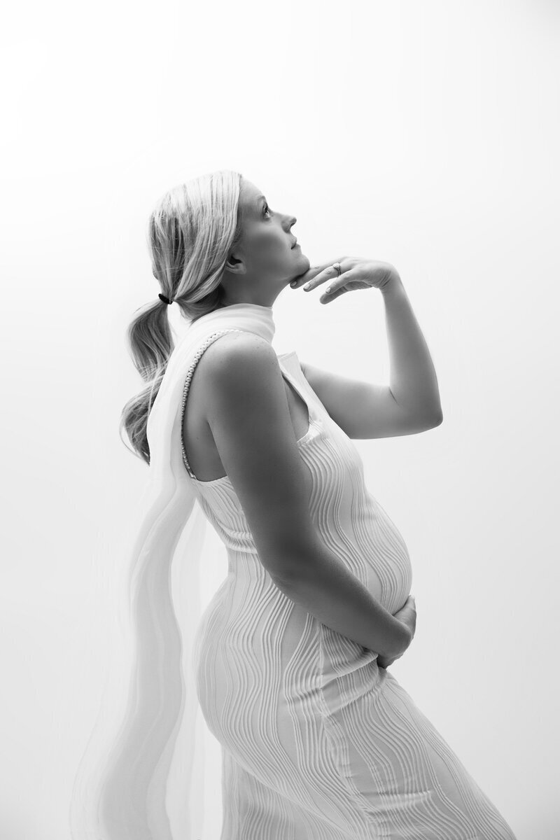 Pregnant mom wearing white dress posing in side profile, by maternity photographer nj
