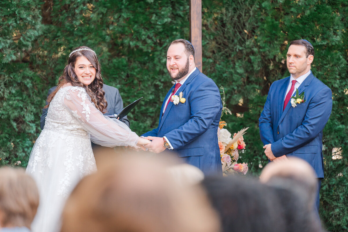A bride and groom holding hands at their wedding altar laughing as they say their vows enjoying their Raleigh wedding photos
