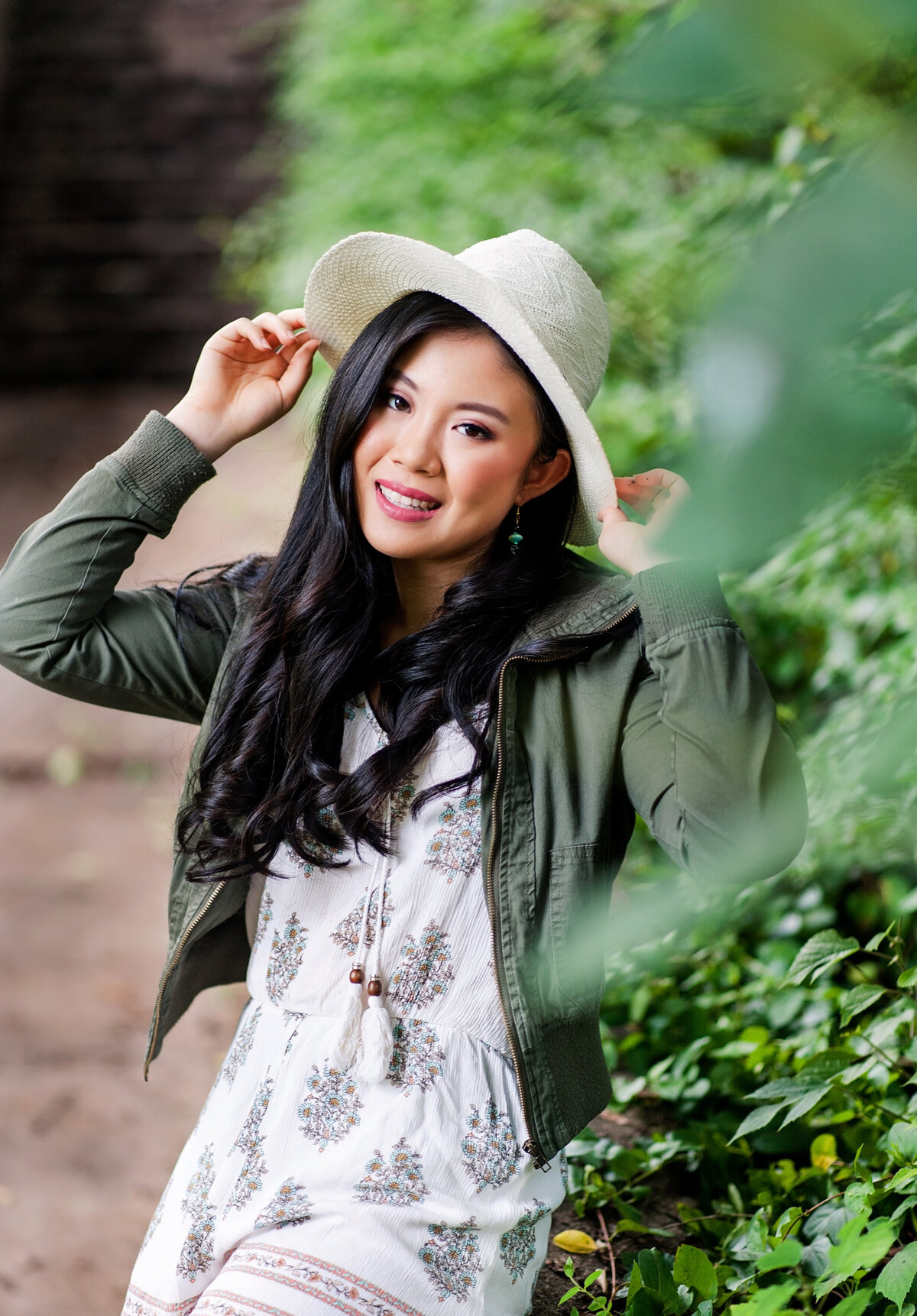 Maggie Walker high school senior girl poses at Libby Hill Park wearing green jacket and hat for her senior portraits.