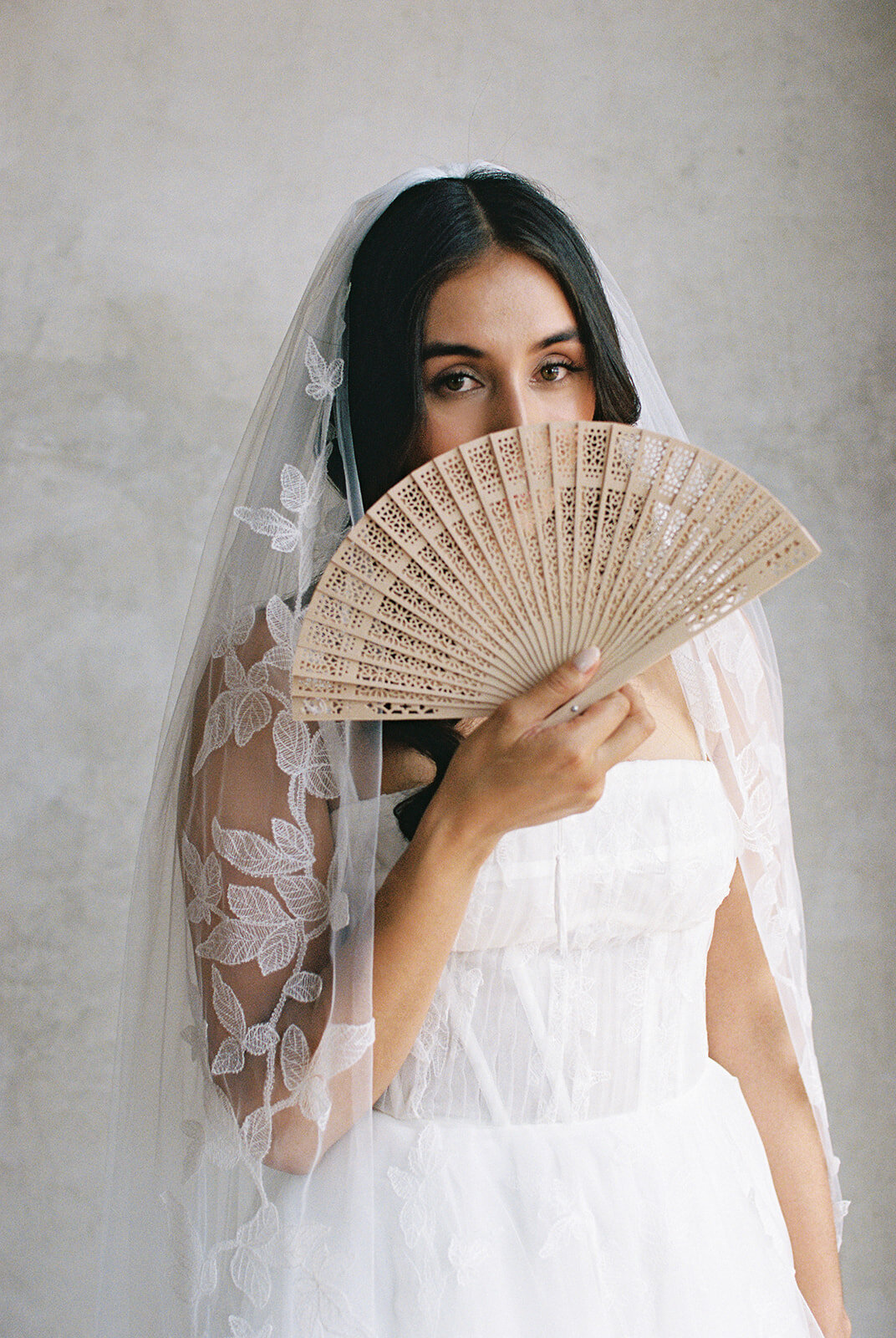 bride poses with folding fan in wedding dress