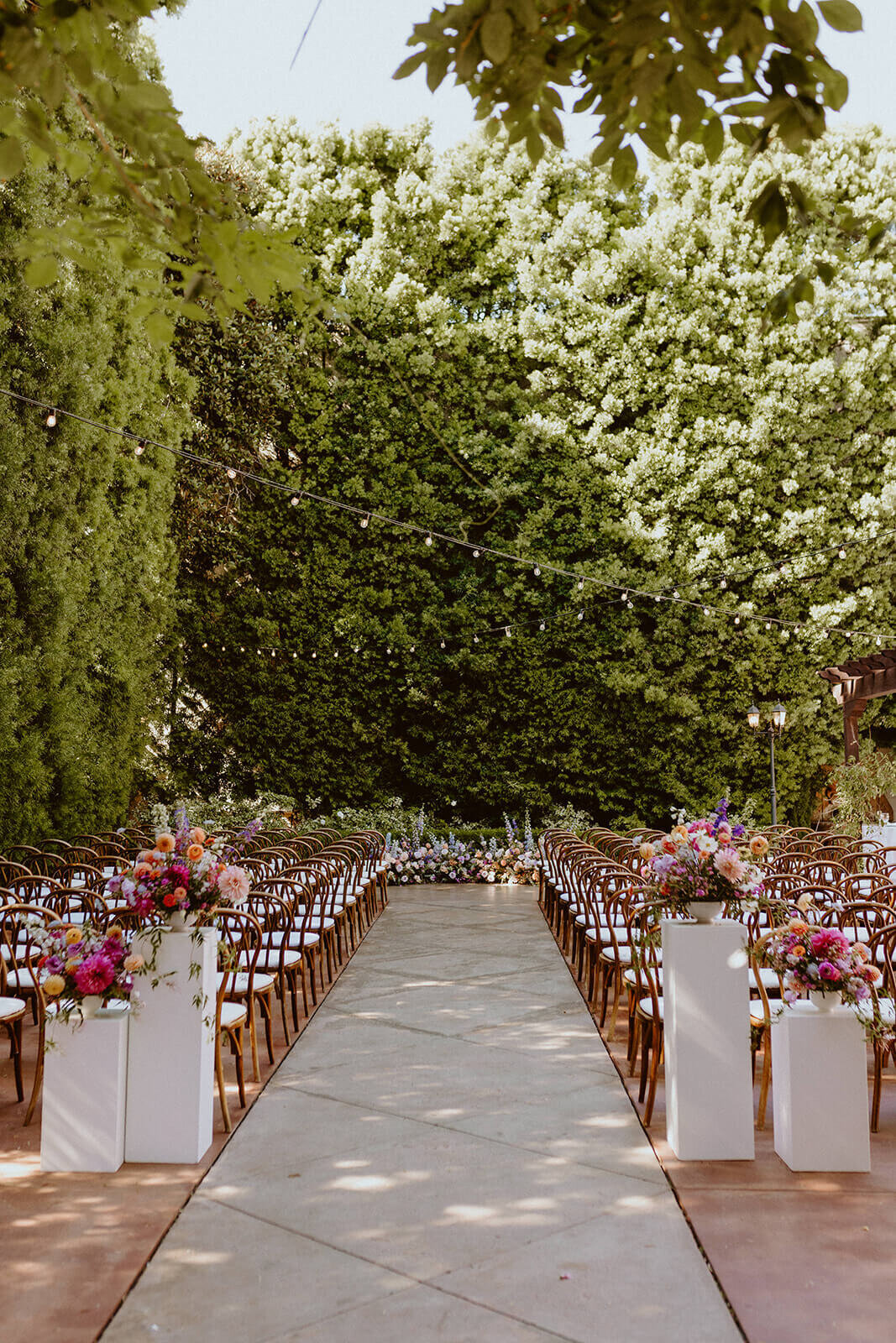 Franciscan Gardens ceremony space with white pillars at the aisle entrance with colorful flowers