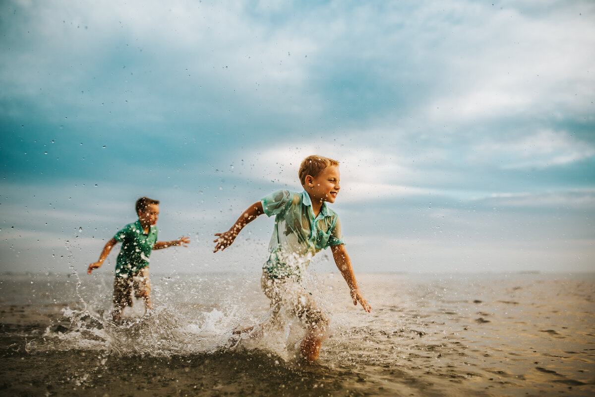 fun portraits of kids running through water at a beach in tarpon springs fl  at sunset