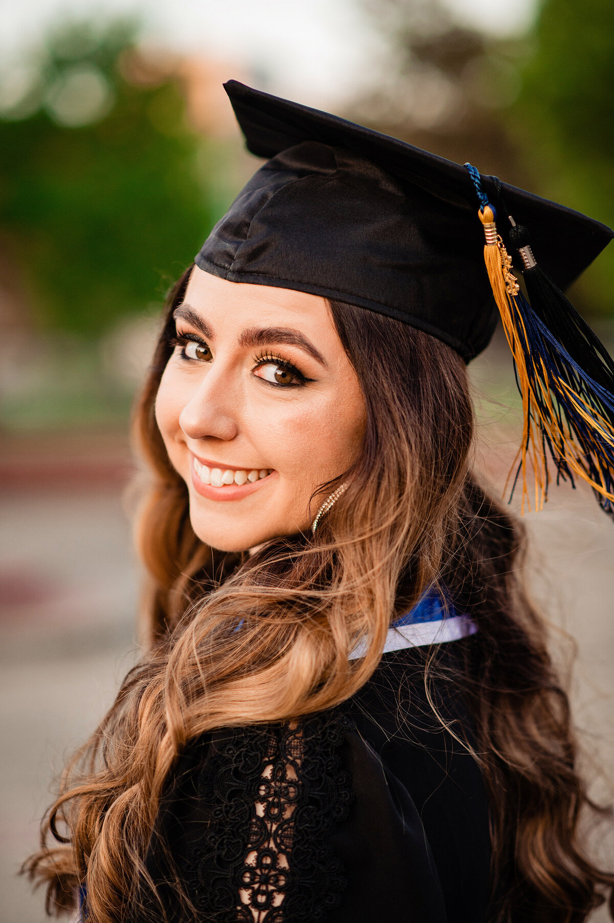 Senior girl wearing cap with all her tassels smiling over her shoulder at the camera