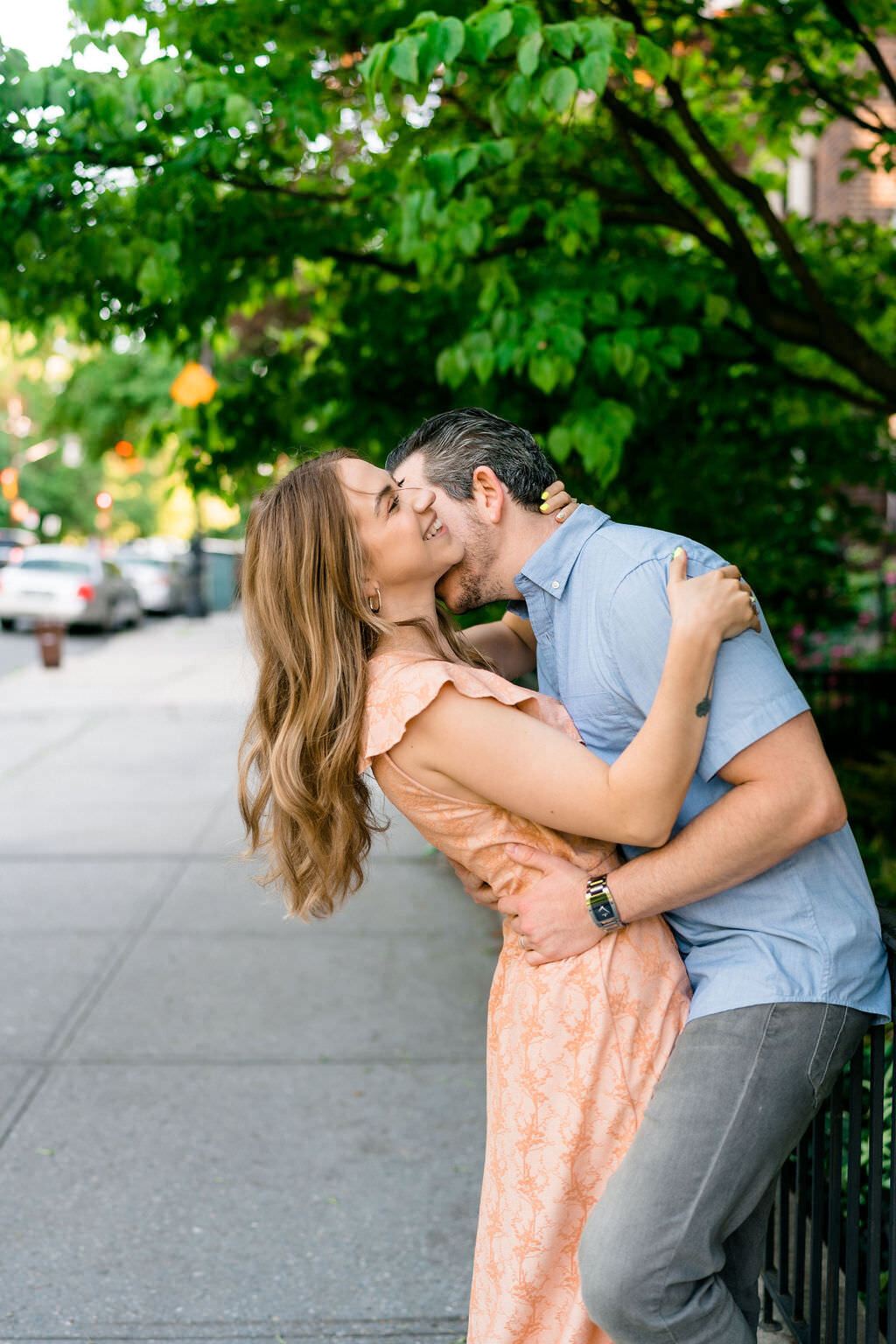couple leaning against as fence hugging as one of them kisses the other's neck