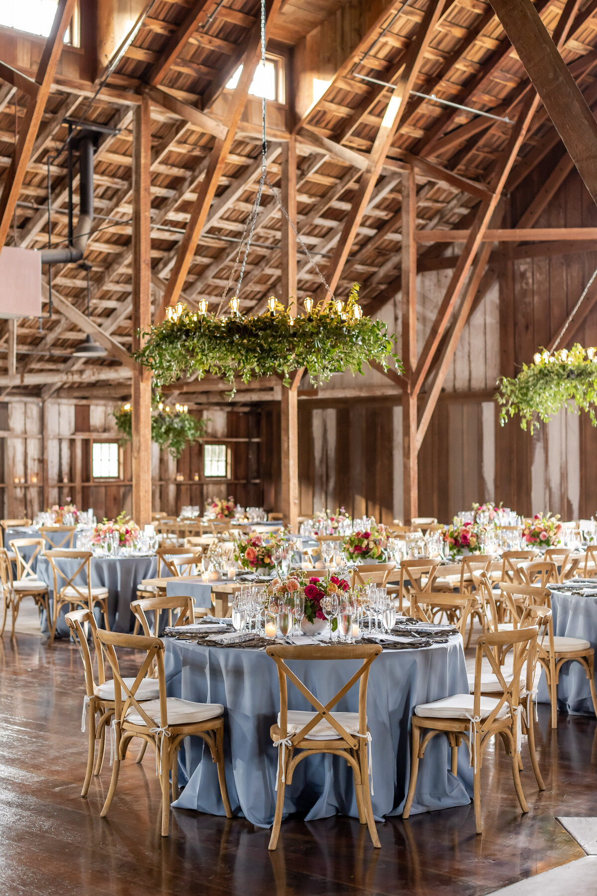 Barn at the Preserve with Blue Tables and Hanging Chandeliers with Greenery
