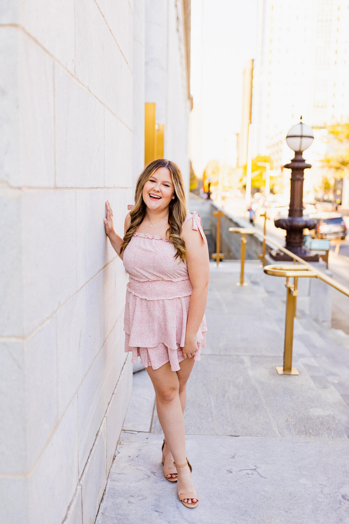Senior Girl downtown in a light pink dress laughing