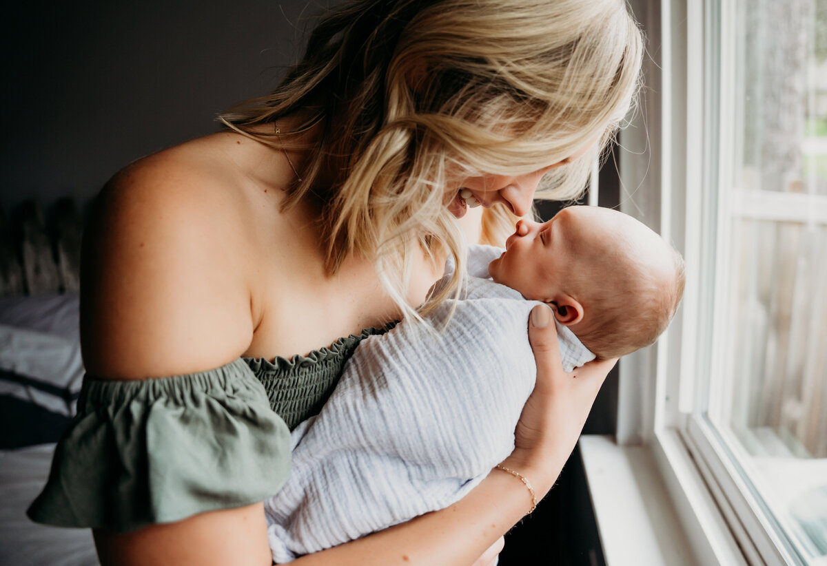 Newborn Photographer, a mother holds her baby closely
