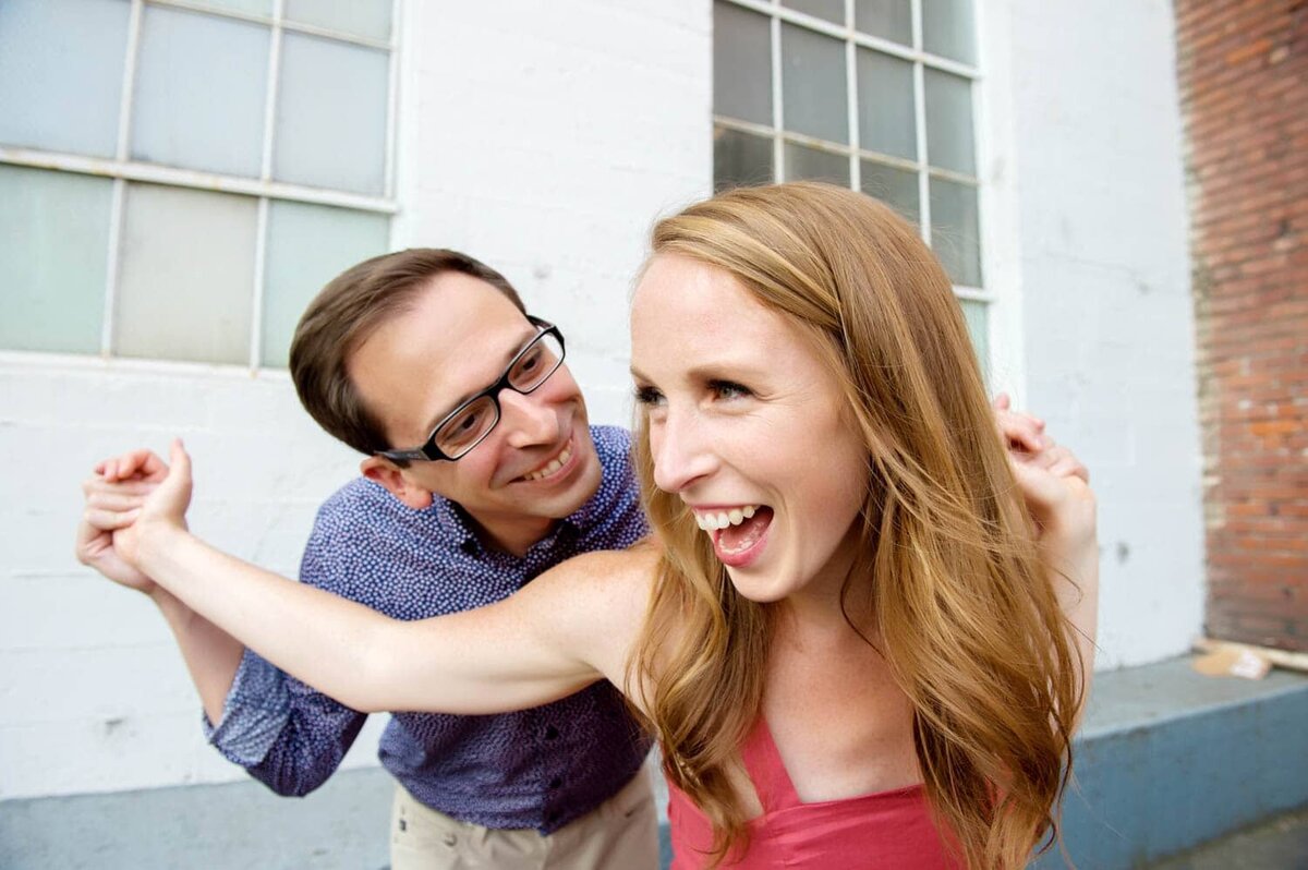 a fun couple pulls each others arms and laughs during their engagement photos
