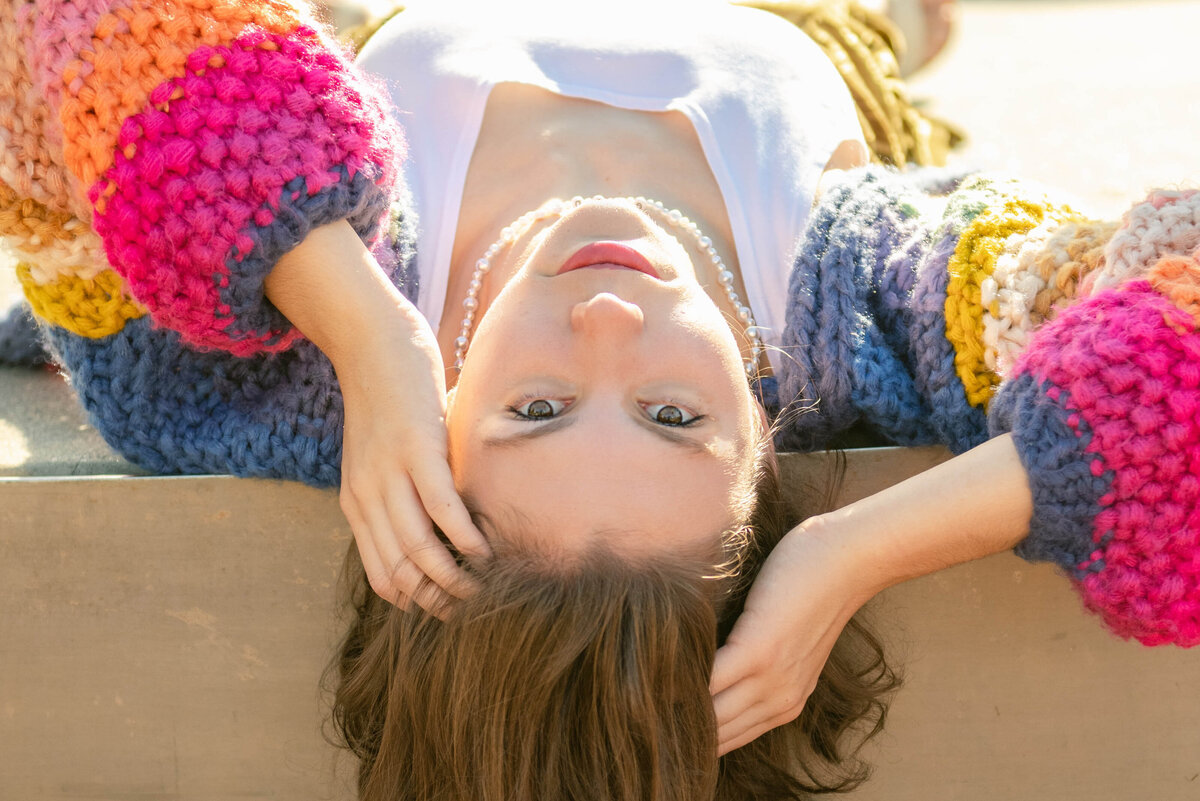 Girl wearing a rainbow sweater, upside down for her Bay Area senior portraits
