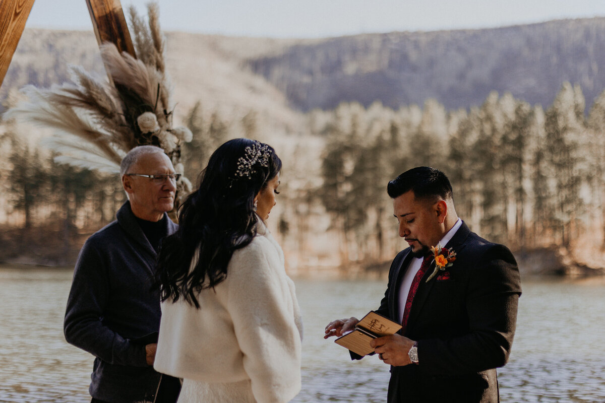 bride and groom exchanging vows in front of Fenton Lake in NM