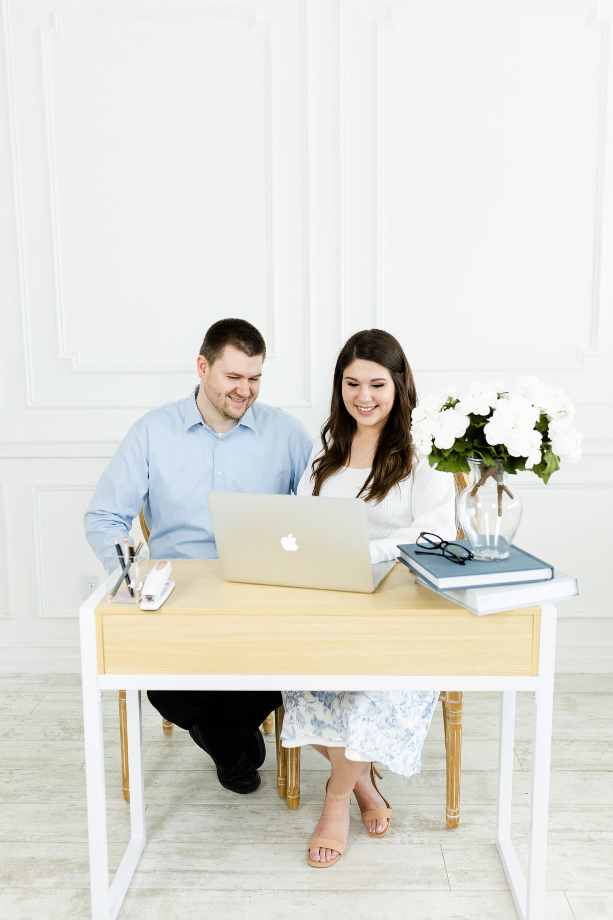 husband and wife sitting at desk for brand photos