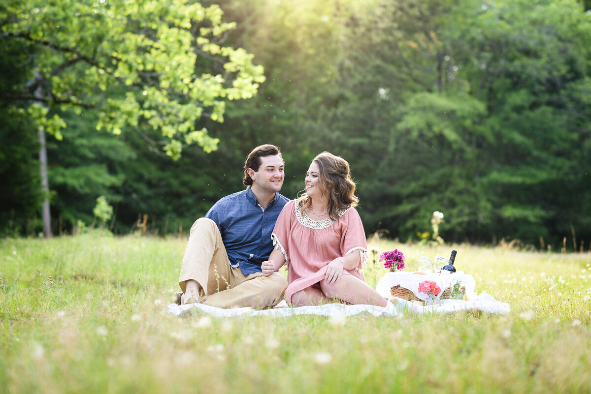 Beautiful Mississippi Engagement Photography: couple looks at each other while enjoying wine at engagement picnic