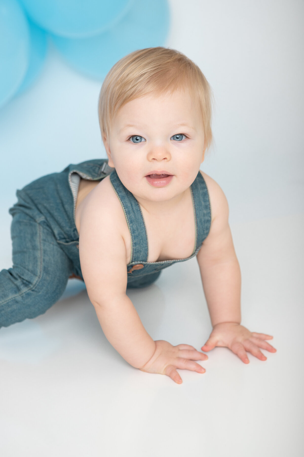 Baby with blue eyes and denim overalls