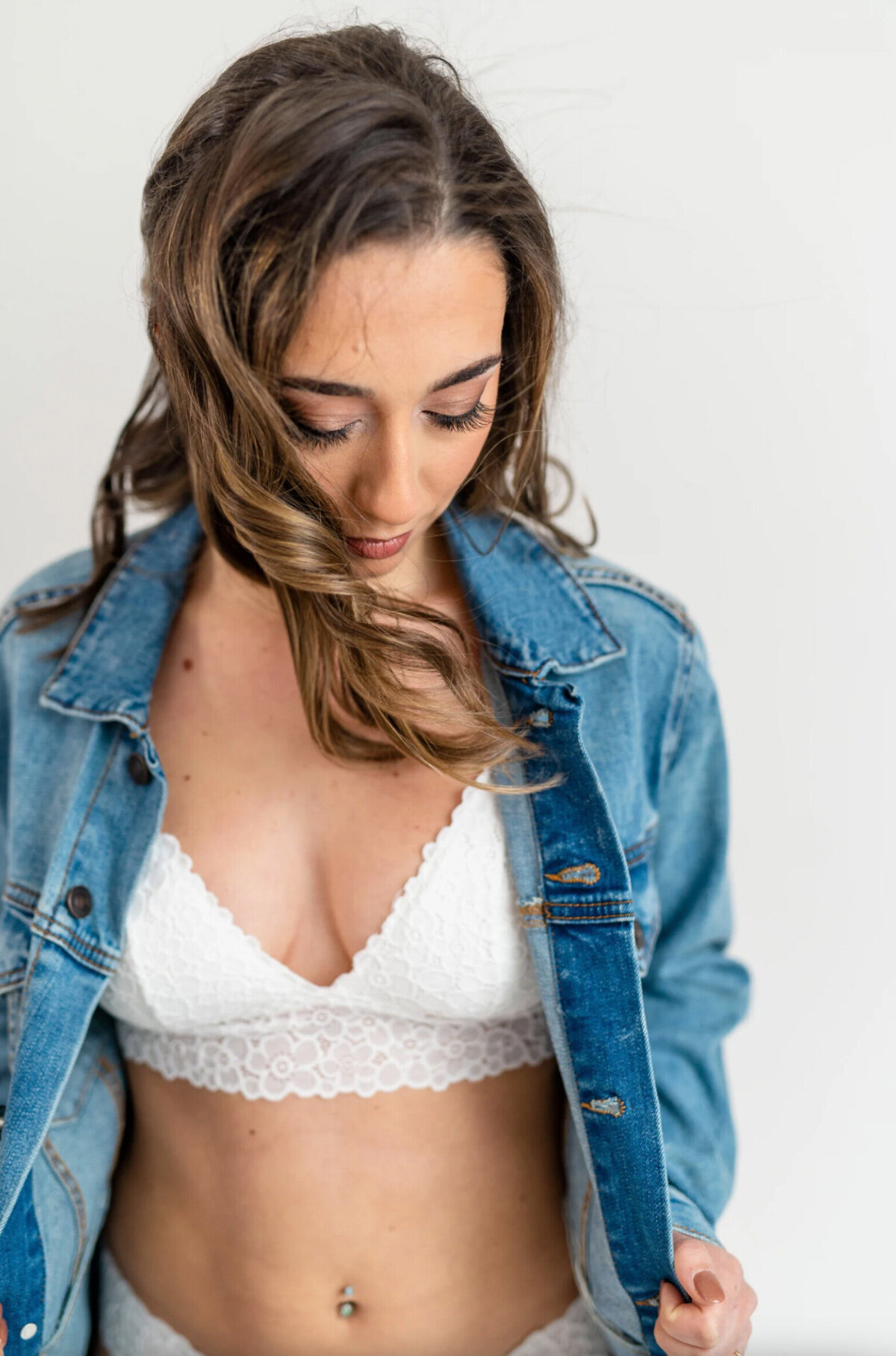 Brunette woman wearing white lingerie, and a jean jacket on a white background
