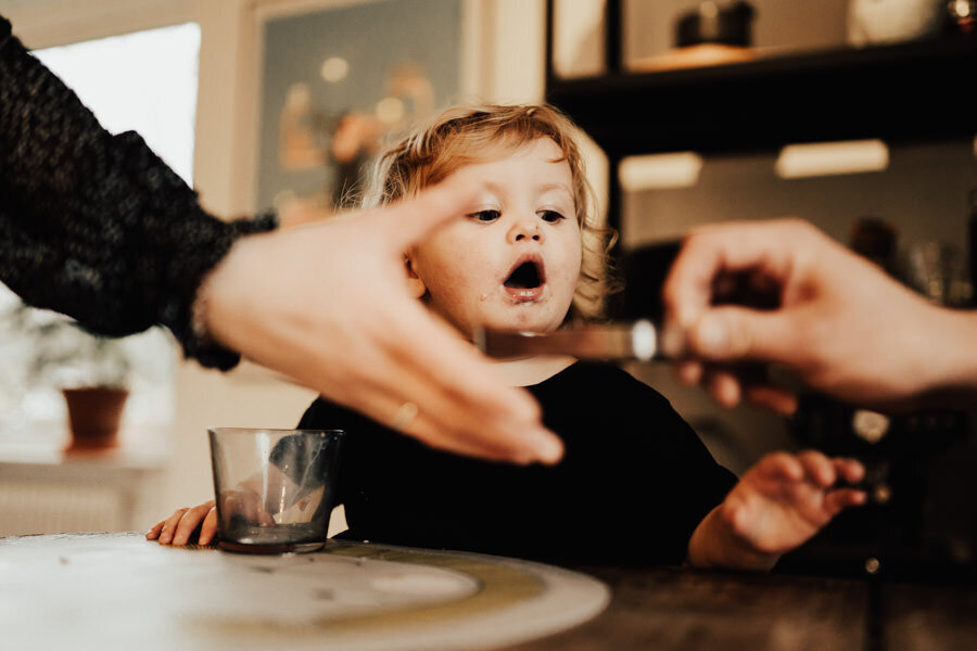 barn sträcker sig efter fika vid matbord under lifestylefotografering