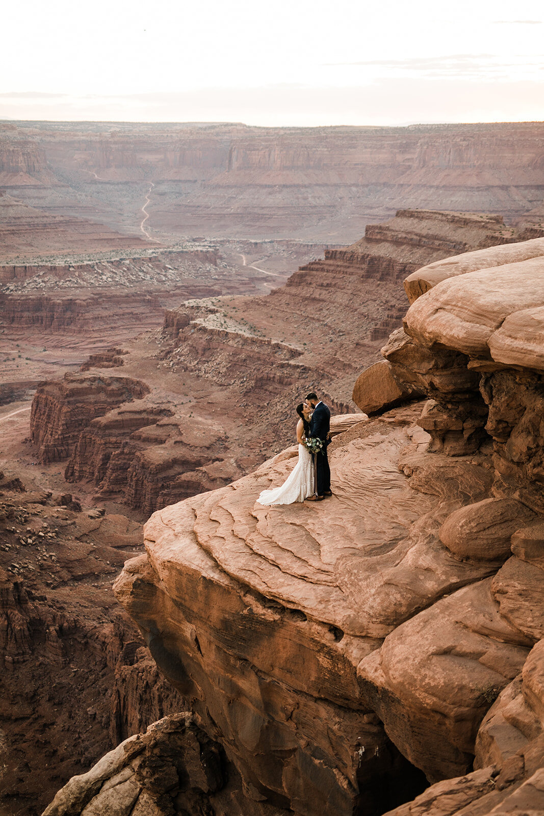Couple standing at the edge of a cliff in Utah elopement