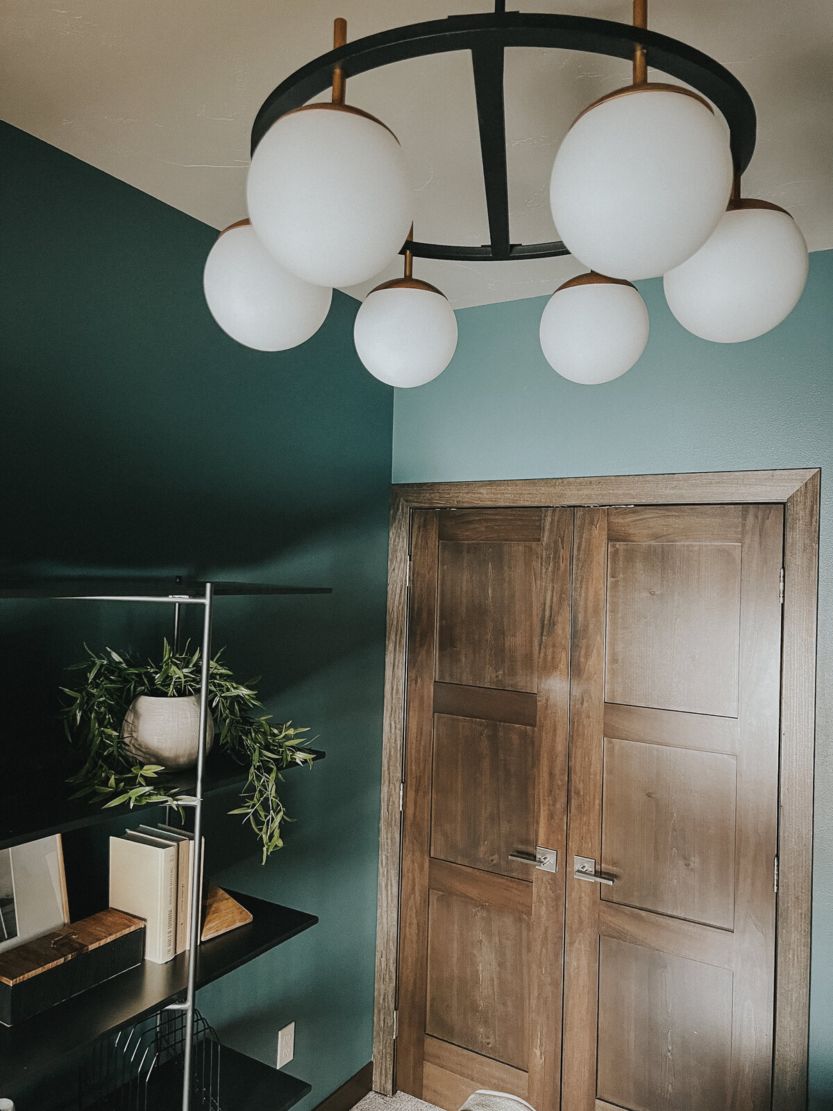A round light fixture hangs from the middle of the room in a green office