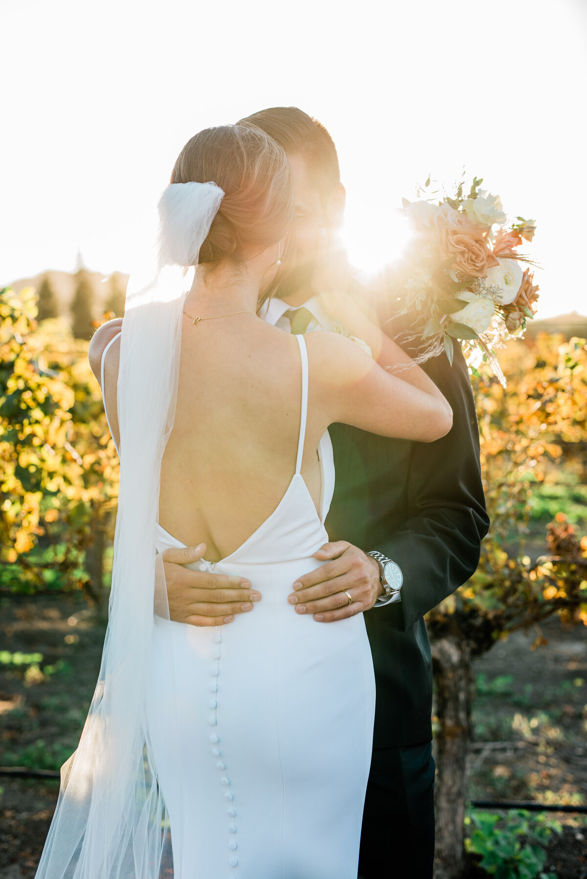 Bride and groom embrace at sunset in the vineyards during their San Luis Obispo wedding for golden hour romantic wedding photos.