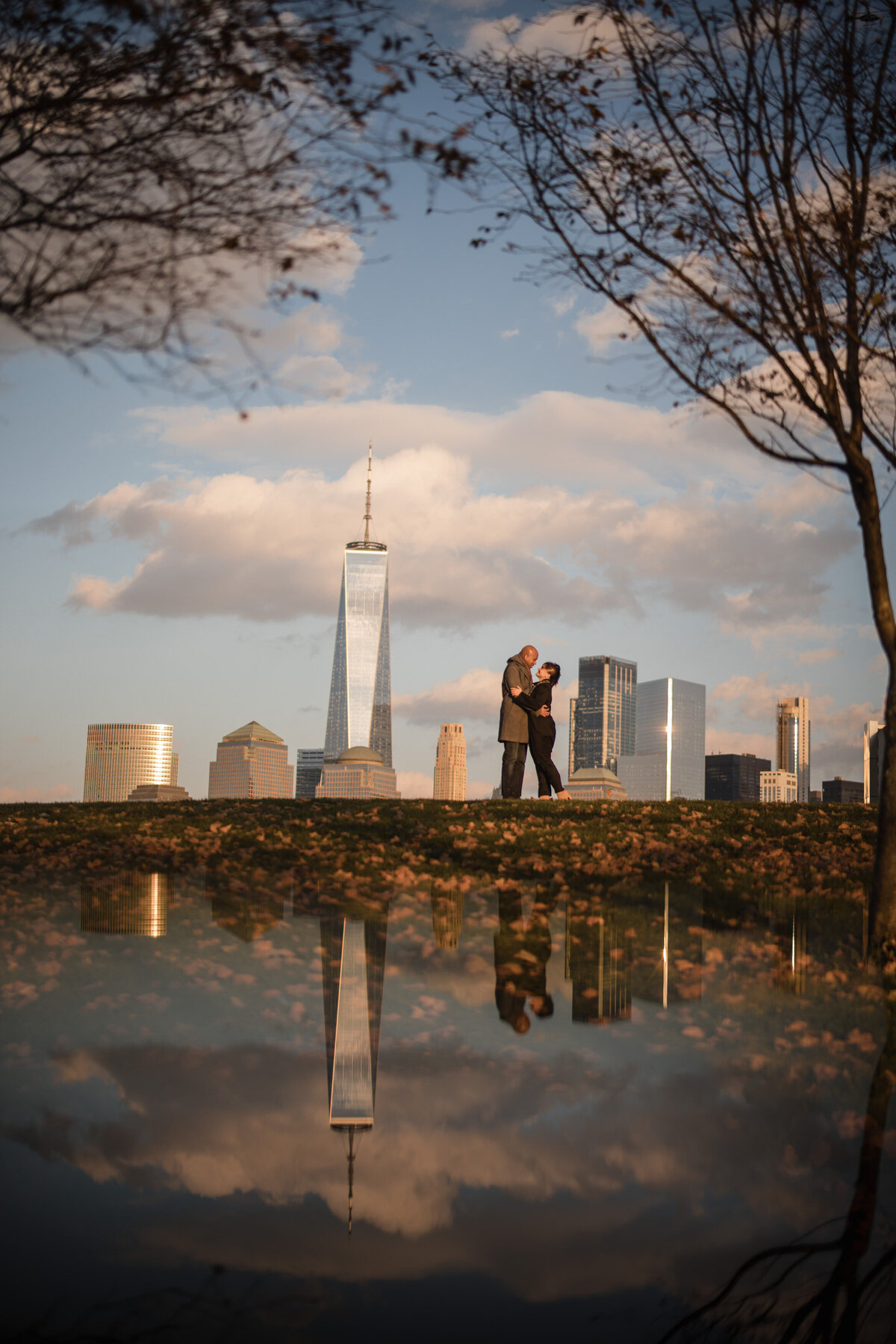 A man and woman standing at the edge of a park with a view of the New York skyline.