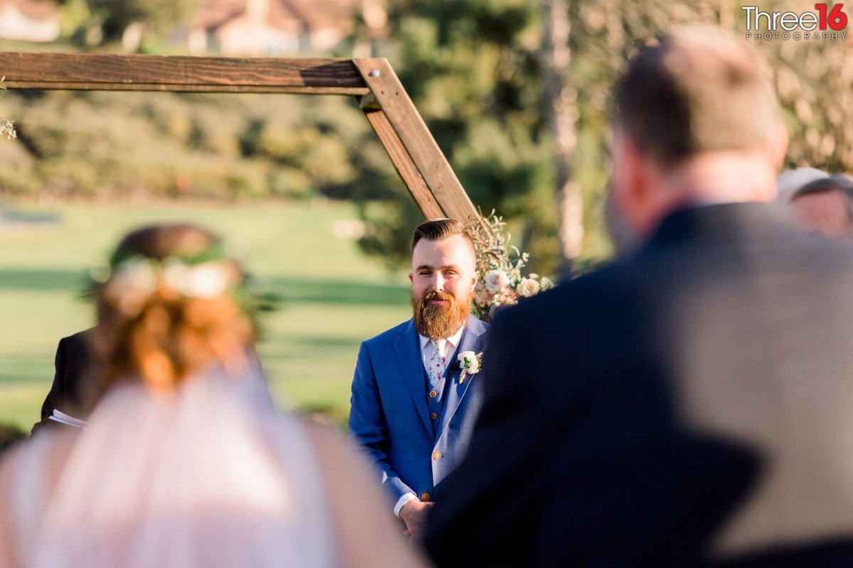 Groom waits at the altar as his Bride is escorted by her father