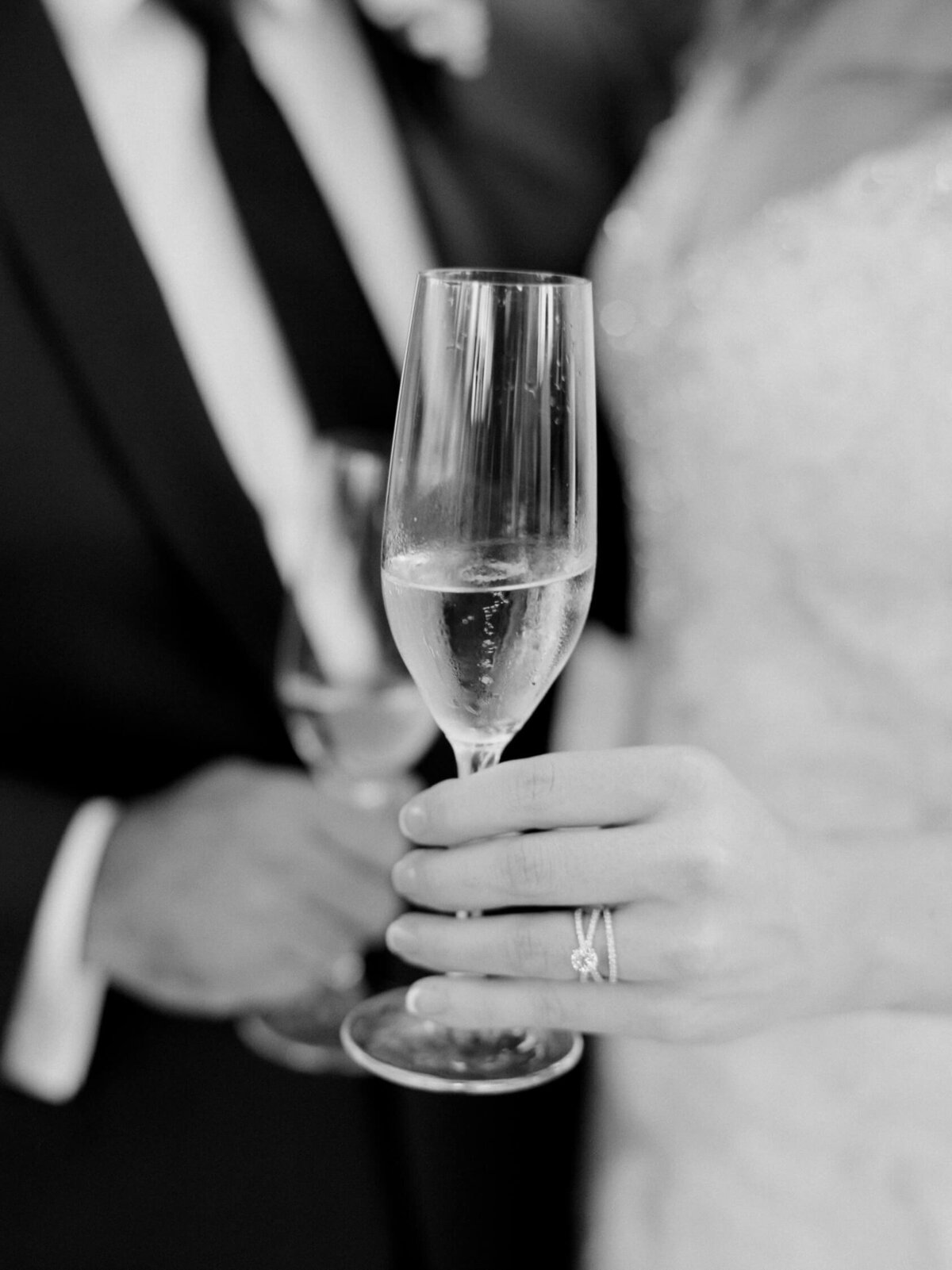Bride and groom hold champagne glasses and come together after their union.