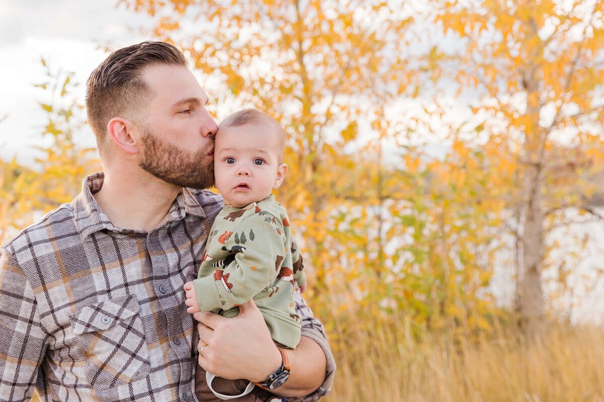 dad kisses sons head while baby looks at camera, Longmont, CO