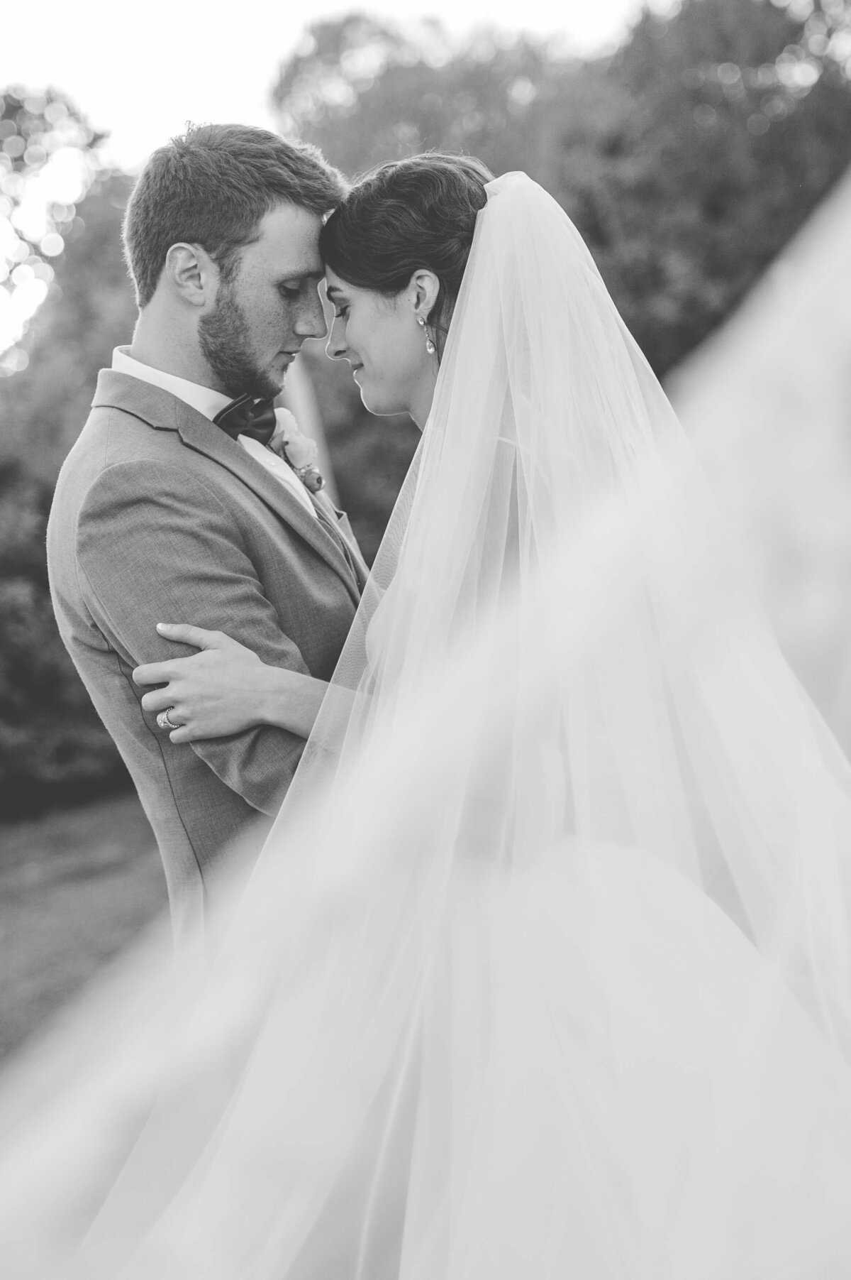 Black and white Ottawa wedding photography of a bride and groom embracing with a flowing veil